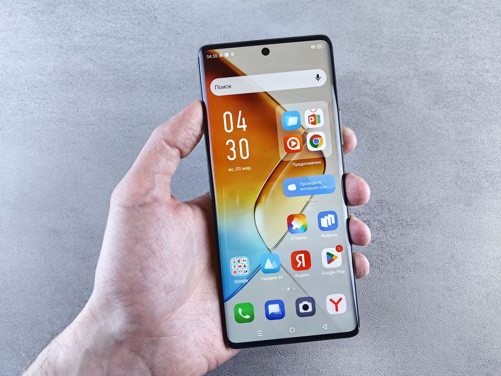 Una mano tiene uno smartphone con la schermata delle app su uno sfondo grigio